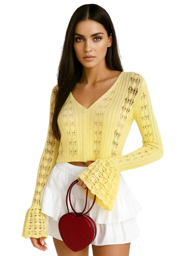 Woman wearing a yellow flare sleeve cardigan and white skirt with a red handbag on a white background